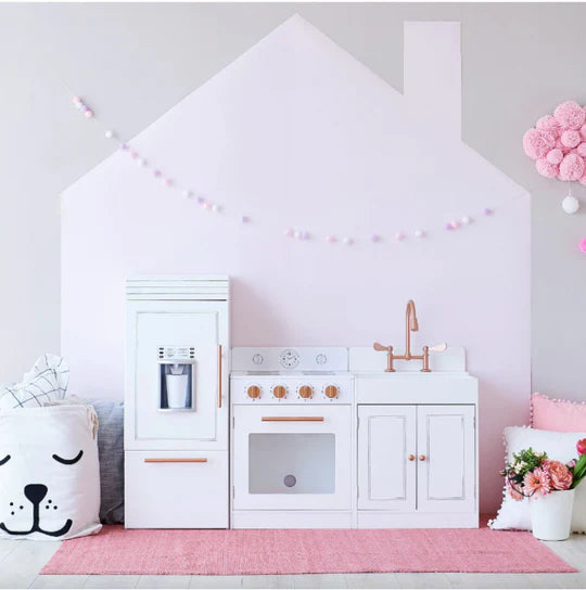 White Teamson kids play kitchen sits infront of a pink wall.